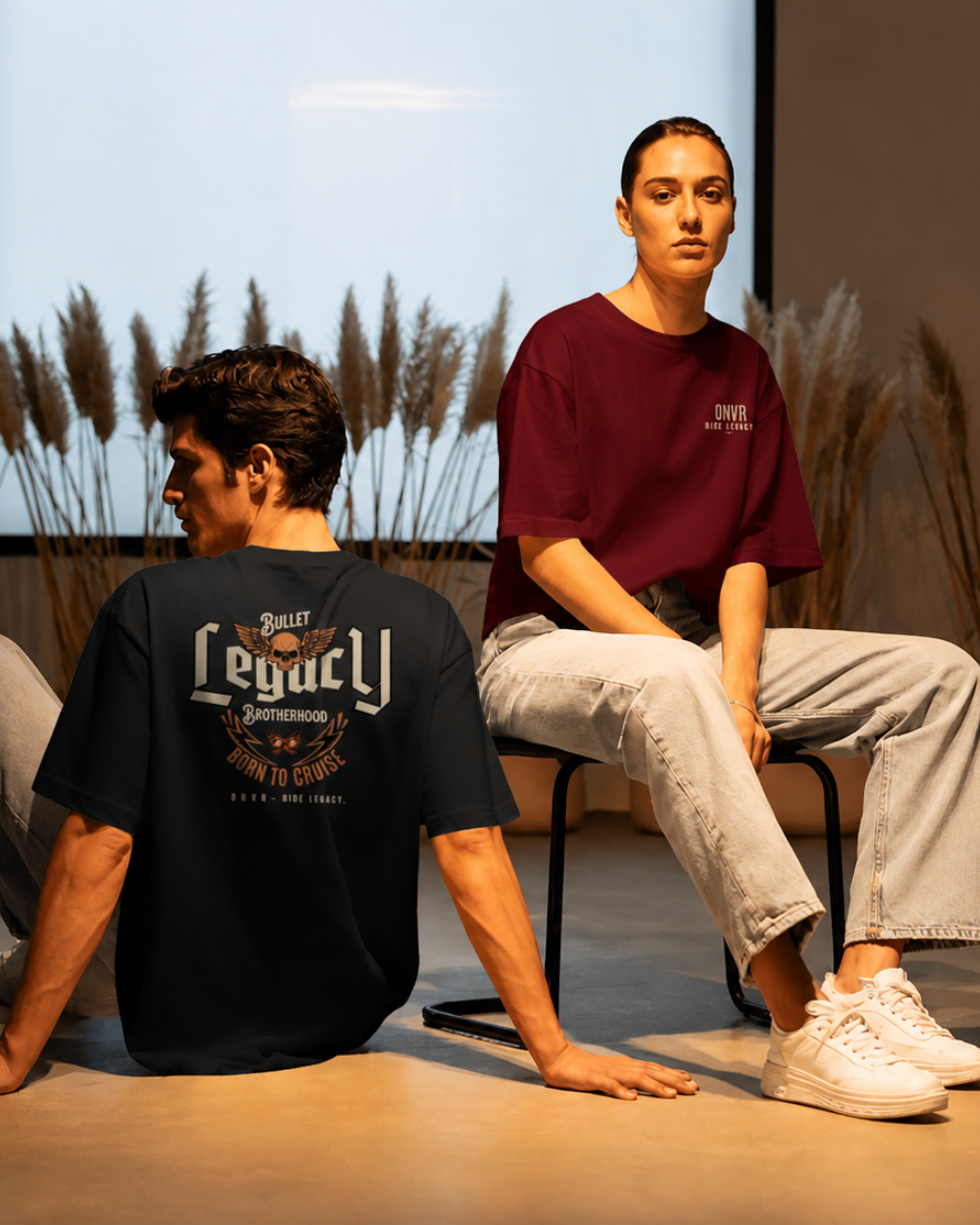 Two people sitting on chairs with 'Bullet Legacy' t-shirts, one black and one maroon.