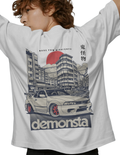 Person wearing a white t-shirt with a graphic design of a car and cityscape, featuring the word 'demonsta'.