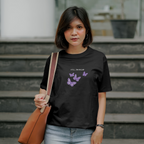 Woman wearing a black t-shirt with 'Shoreditch London' text, standing outdoors.