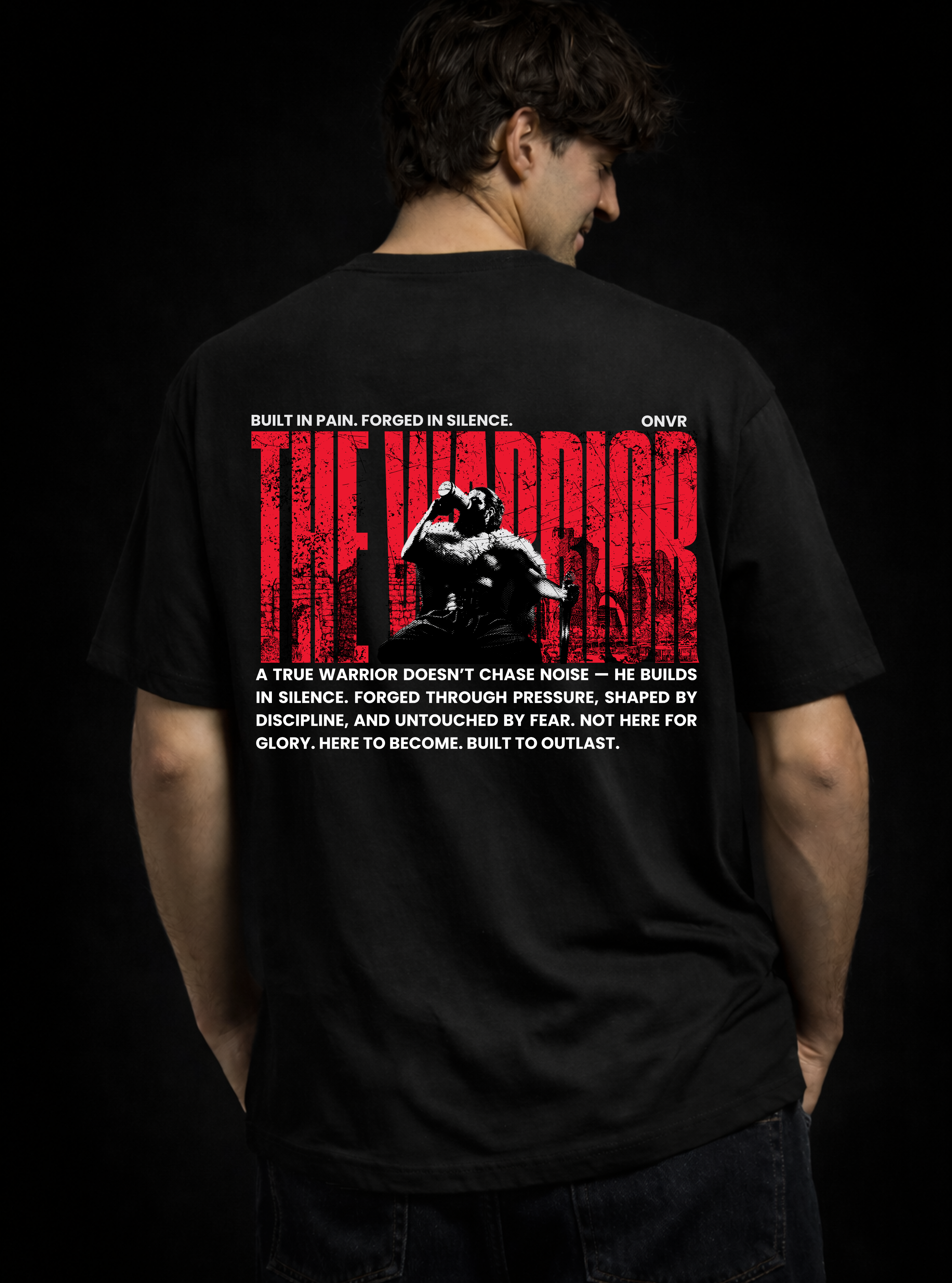Person wearing a black t-shirt with 'The Warrior' design on the back against a dark background