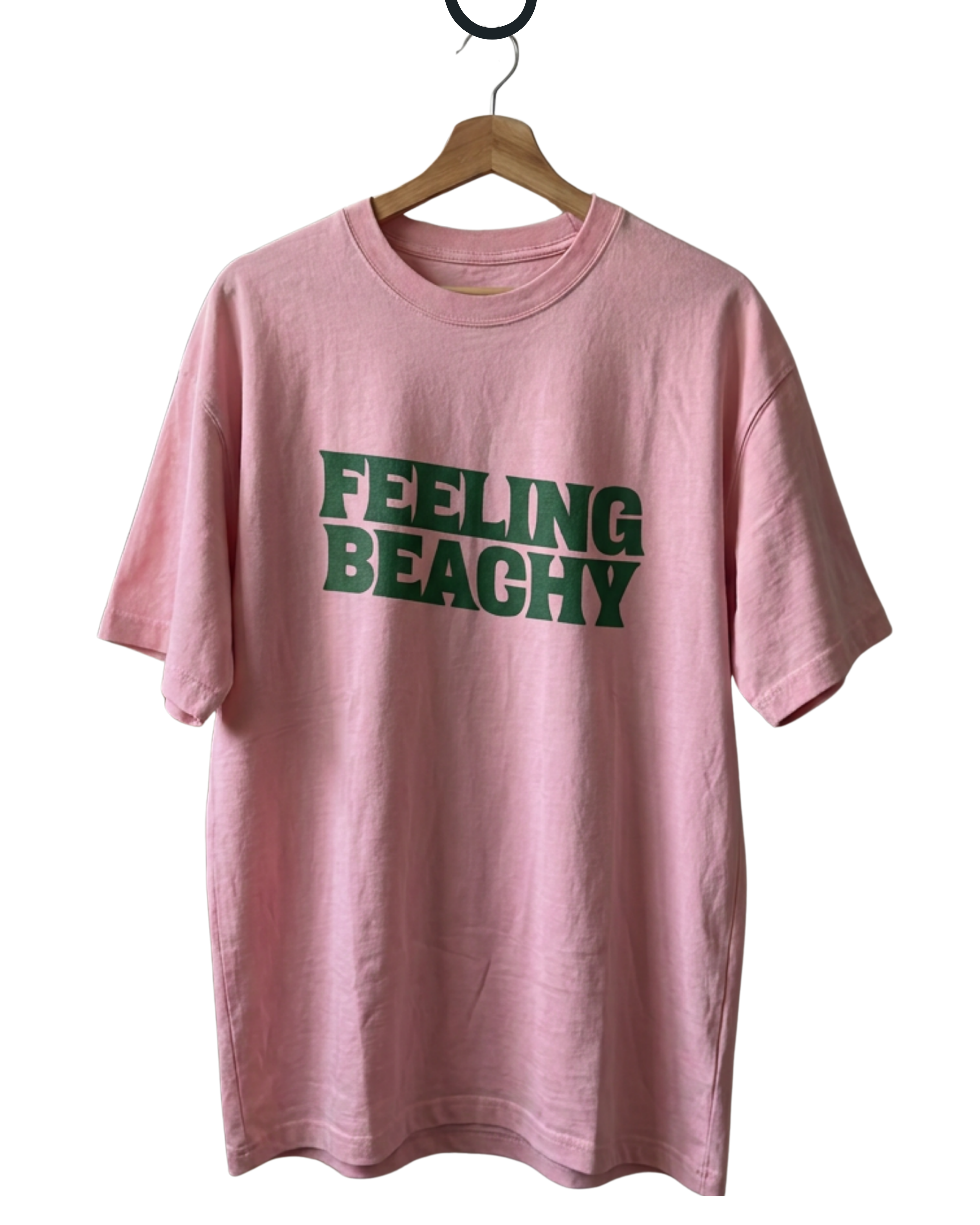 Pink t-shirt with 'FEELING BEACHY' text in green on a hanger against a white background