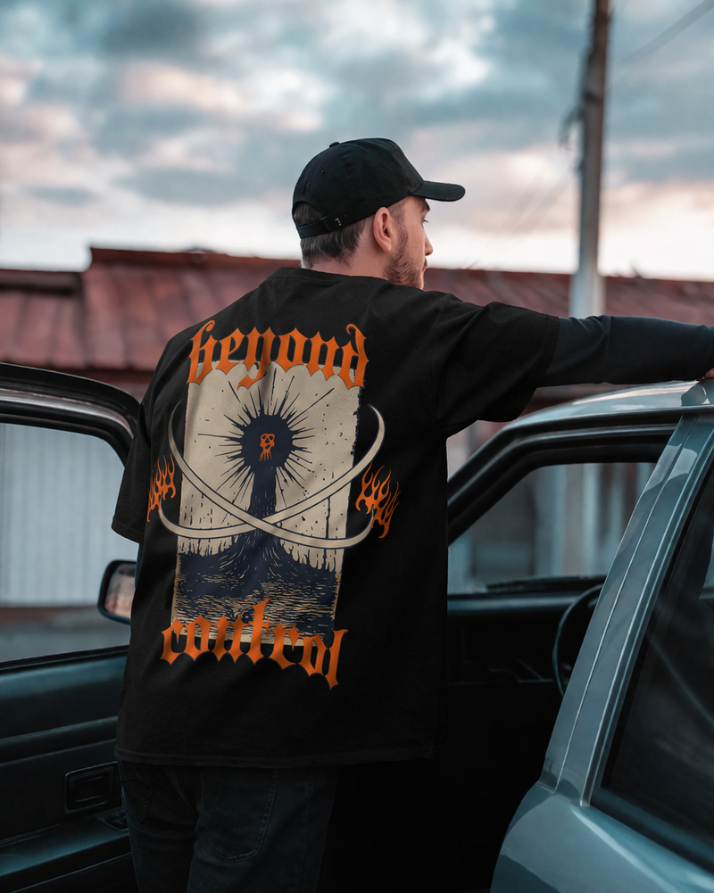Person wearing a black sweatshirt with a graphic design, standing next to a car.