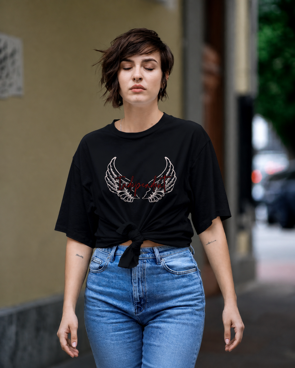 Woman wearing a black t-shirt with a graphic design and blue jeans on a city street.