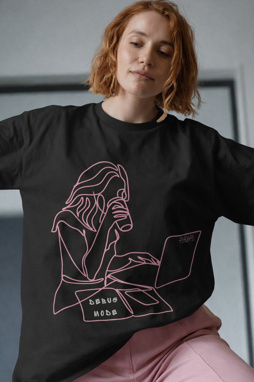 Person wearing a black t-shirt with a pink graphic design and text.