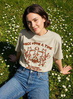 Person wearing a t-shirt with a graphic design in a grassy field with flowers