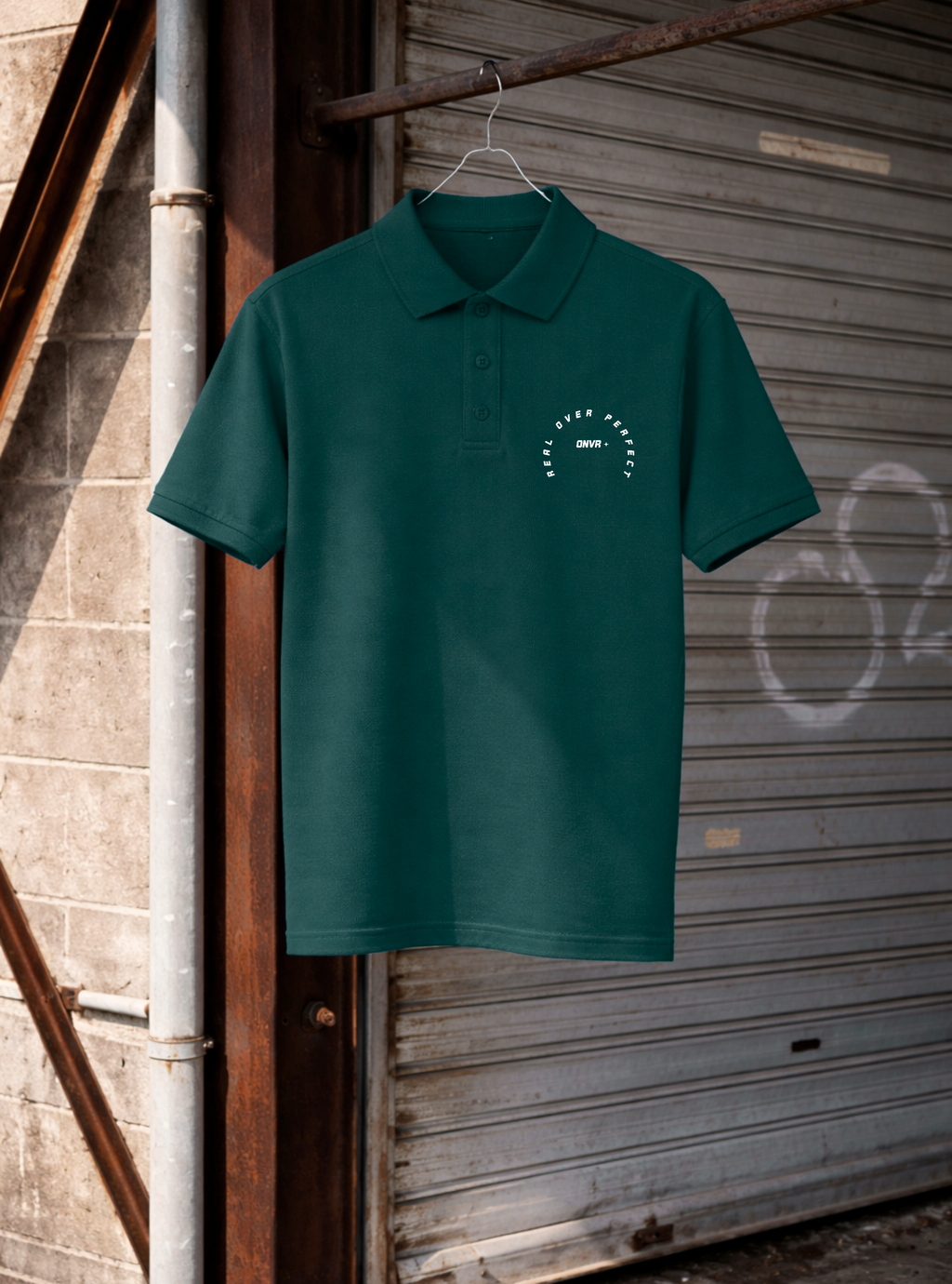 Green polo shirt with a logo hanging on a metal hook against a rustic background.