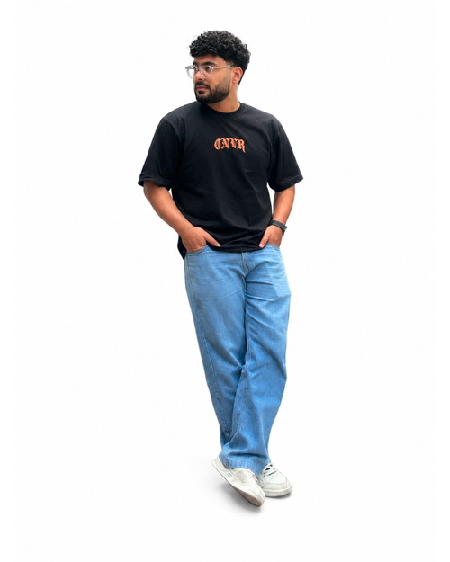 Model wearing a ONVR black t-shirt with orange text, blue jeans, and white sneakers on a white background